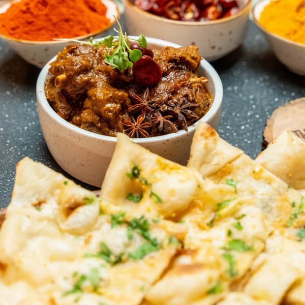 Indian lamb curry with star anise and fresh herbs, served with naan bread and spices.